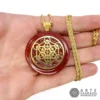 Mano sosteniendo Collar Orgón Cubo de Metatrón en Chapa de Oro de 14k con cuarzo a elegir como Jaspe Rojo con cadena de acero inoxidable sobre fondo blanco